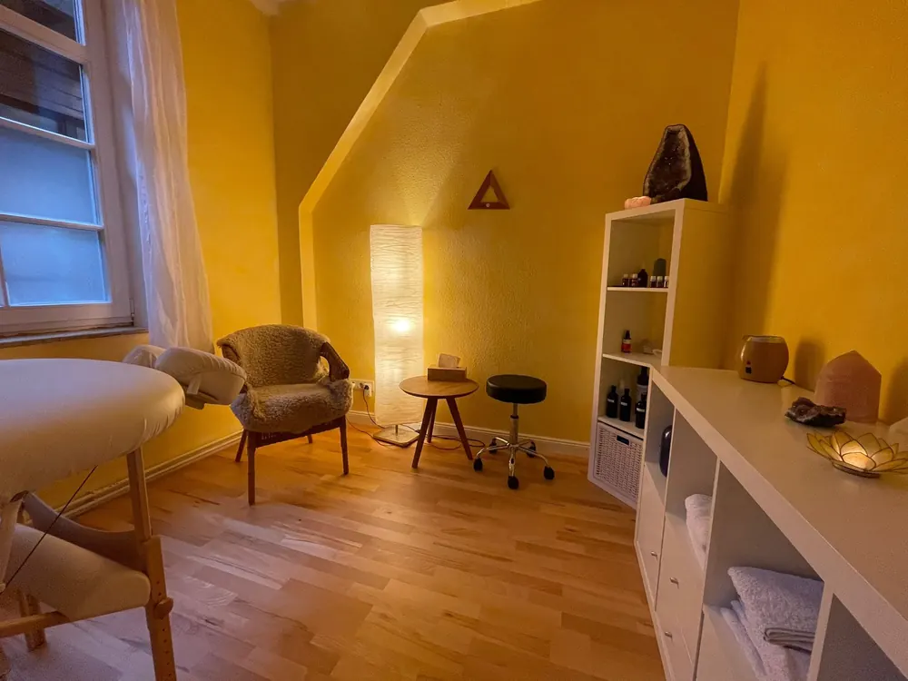 Behandlungsraum des LomiVersums mit Liege, Sessel und warmem Licht